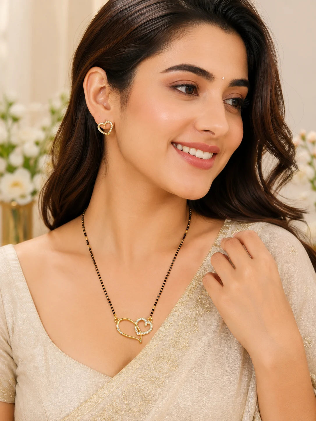 Woman wearing a gold necklace with a heart pendant and matching earrings.
